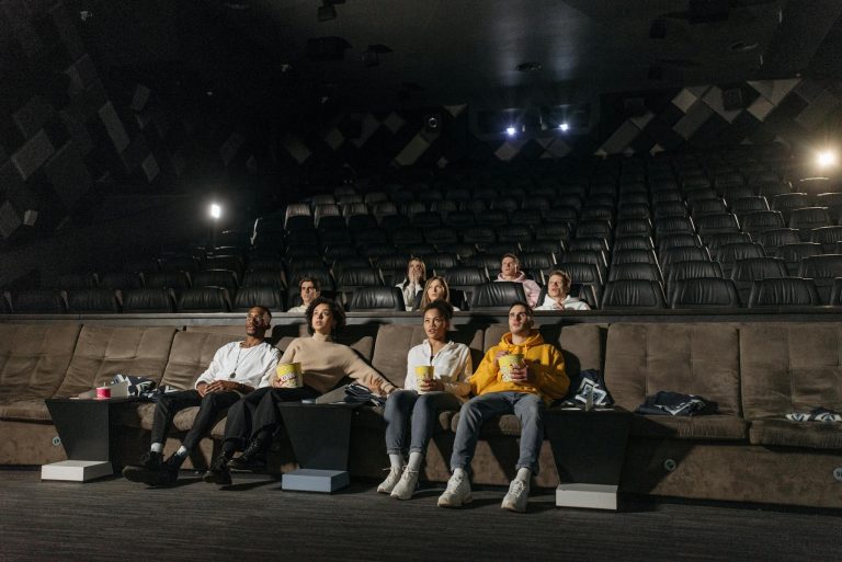 A diverse group of people enjoying a movie screening in an empty cinema with popcorn.