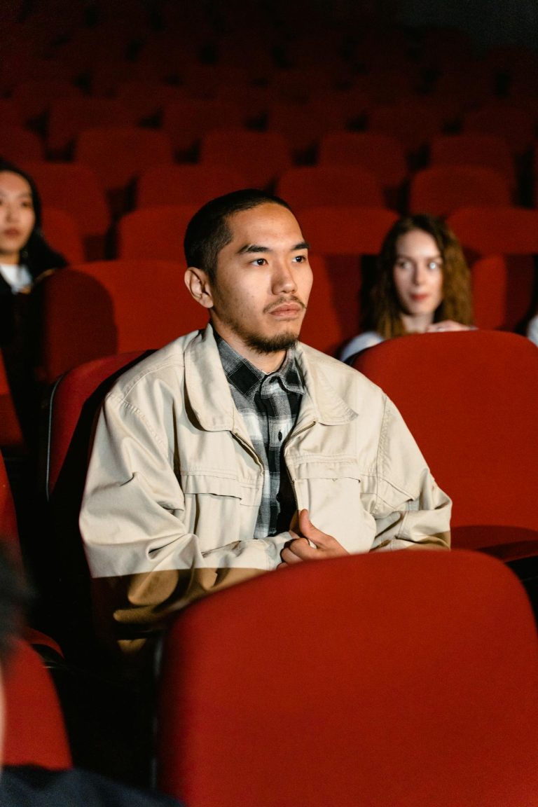 Adult man sitting in a cinema watching a film with others.